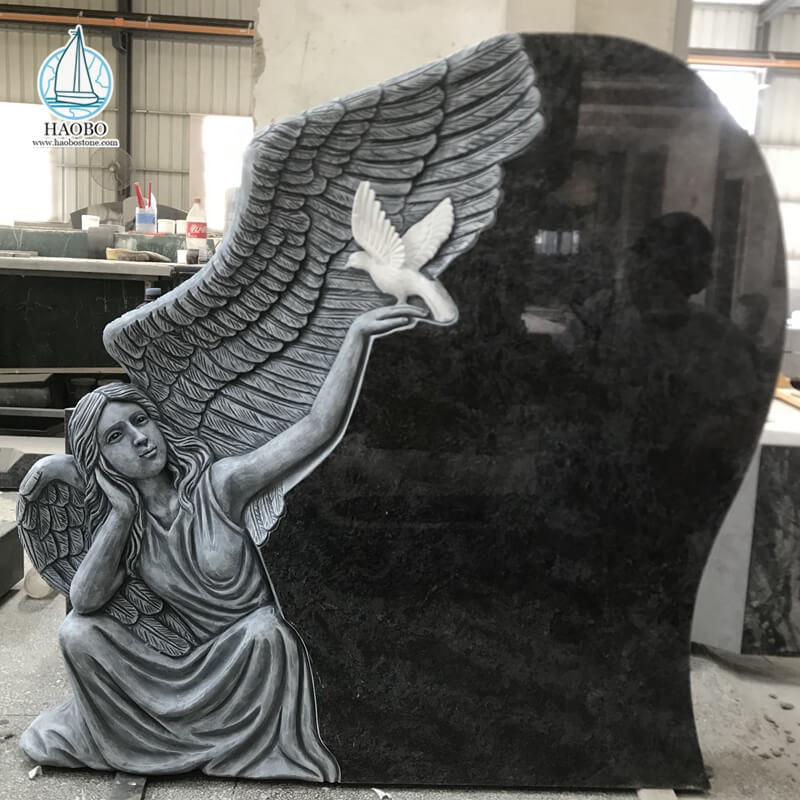 Anjo de granito preto com lápide funerária esculpida em pomba
